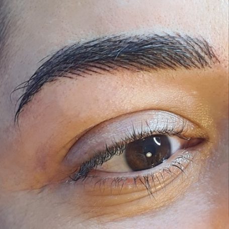 Close-up van een oog met volle wimpers en een goed verzorgde wenkbrauw.